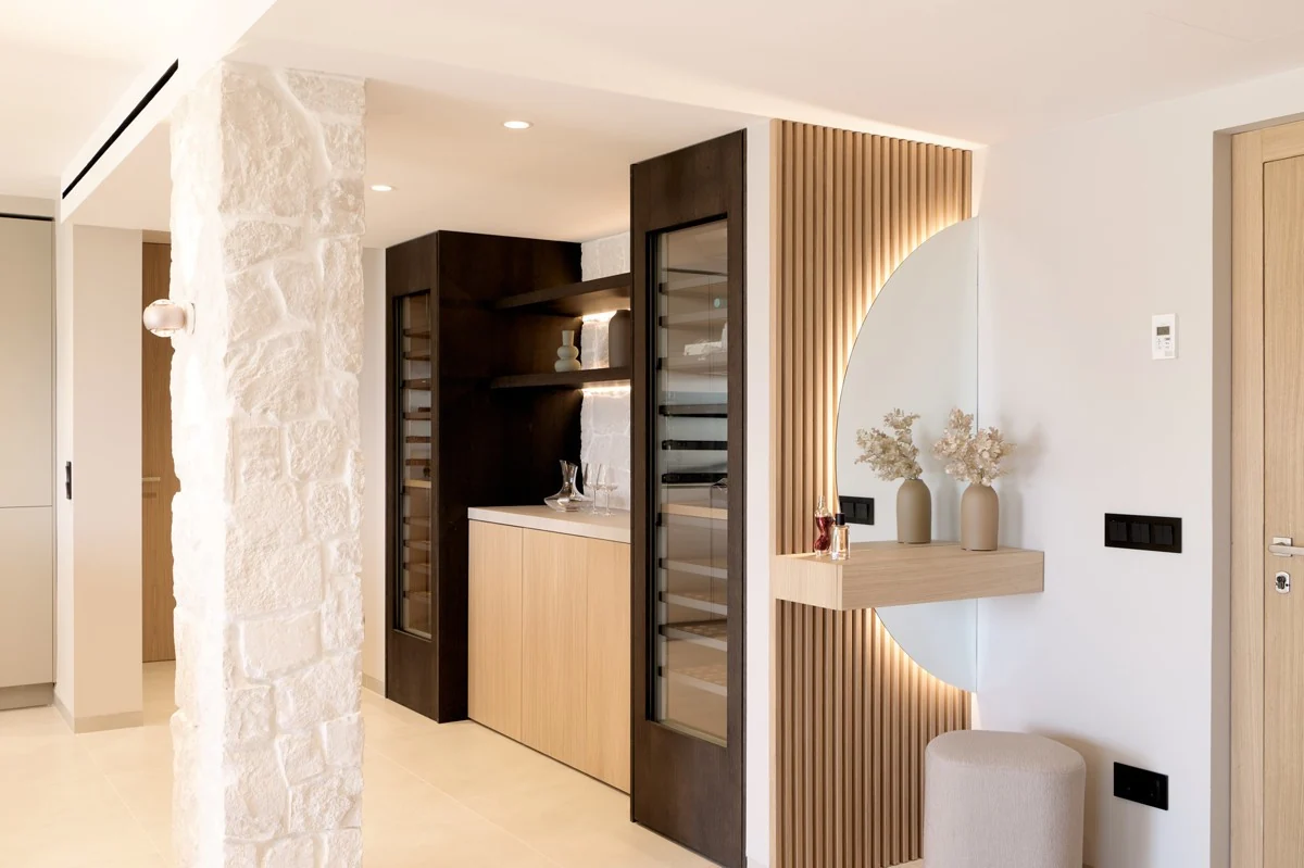 Natural stone, timber cabinetry and a circular mirror in a furnished interior